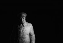 statue of winston churchill standing against a dark background