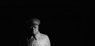 statue of winston churchill standing against a dark background