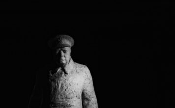 statue of winston churchill standing against a dark background