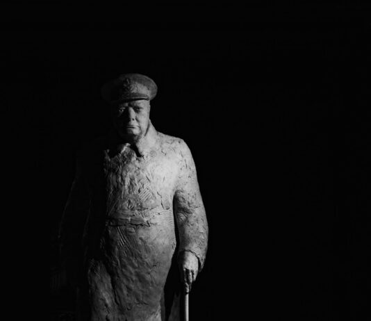 statue of winston churchill standing against a dark background