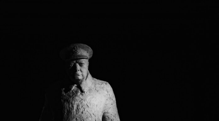 statue of winston churchill standing against a dark background